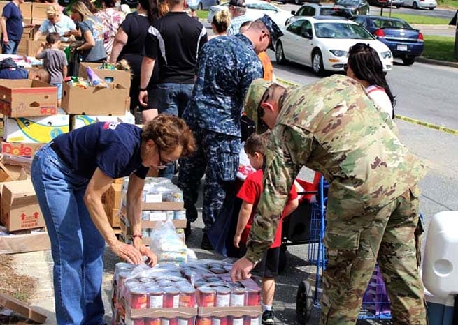 people sorting through boxes of food donations, including veteran