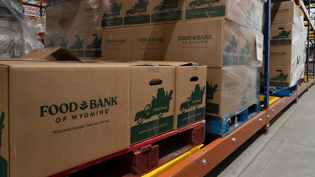 Stacks of Food Bank of Wyoming food boxes stacked on a warehouse shelf.