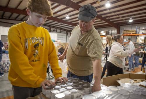 Dad and teen boy volunteering by packing canned goods.