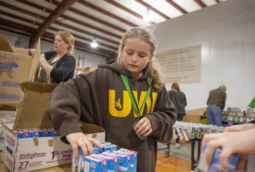 Teen girl packing drink boxes in the Wyoming volunteer center.