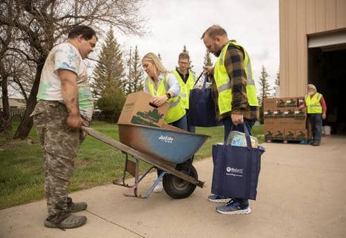 Volunteers help load food box into a wheelbarrow