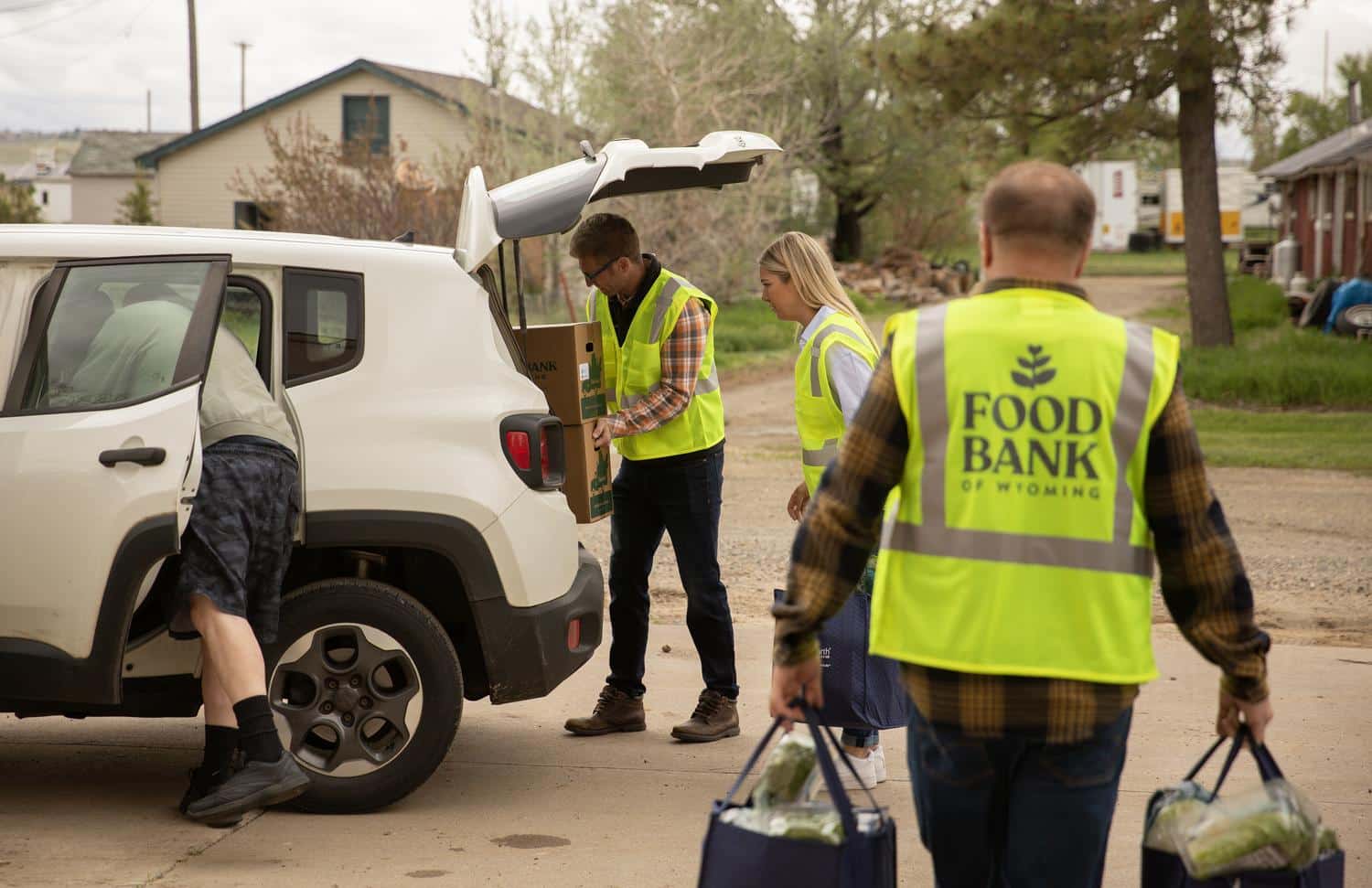 Volunteers loading bags of food into a car.