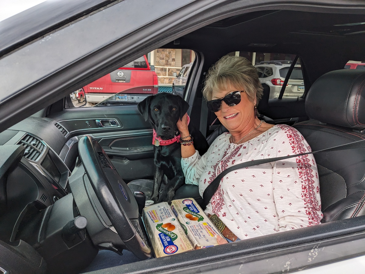 Shirleena and her two-year-old black Labrador, Maddy, in their car at a mobile food pantry in WY