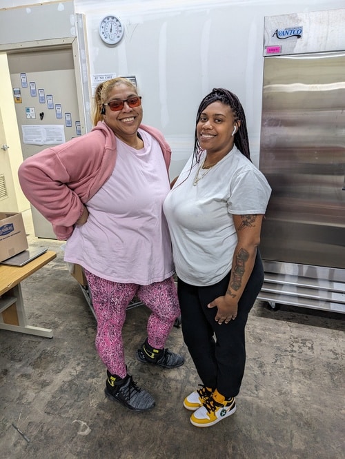 Neighbors posing inside a pantry kitchen