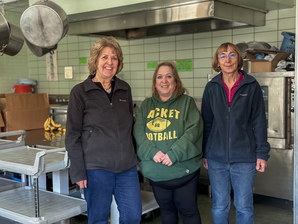 three women standing inside of a commercial kitchen