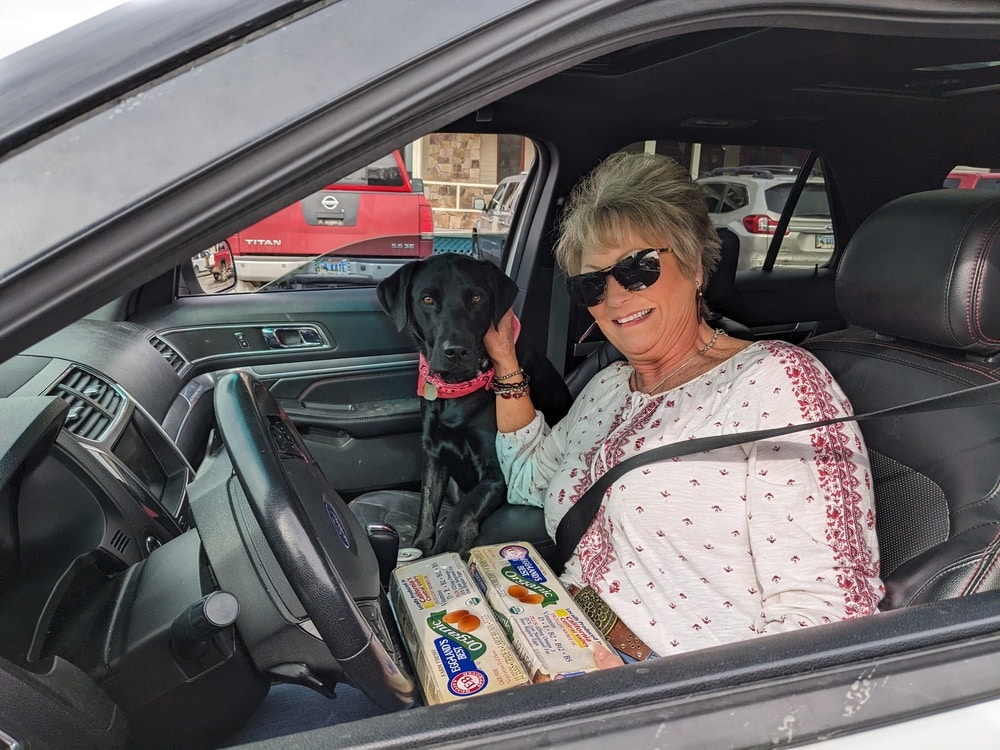 A woman and her dog inside of a car, in line at the Pinedale mobile pantry.