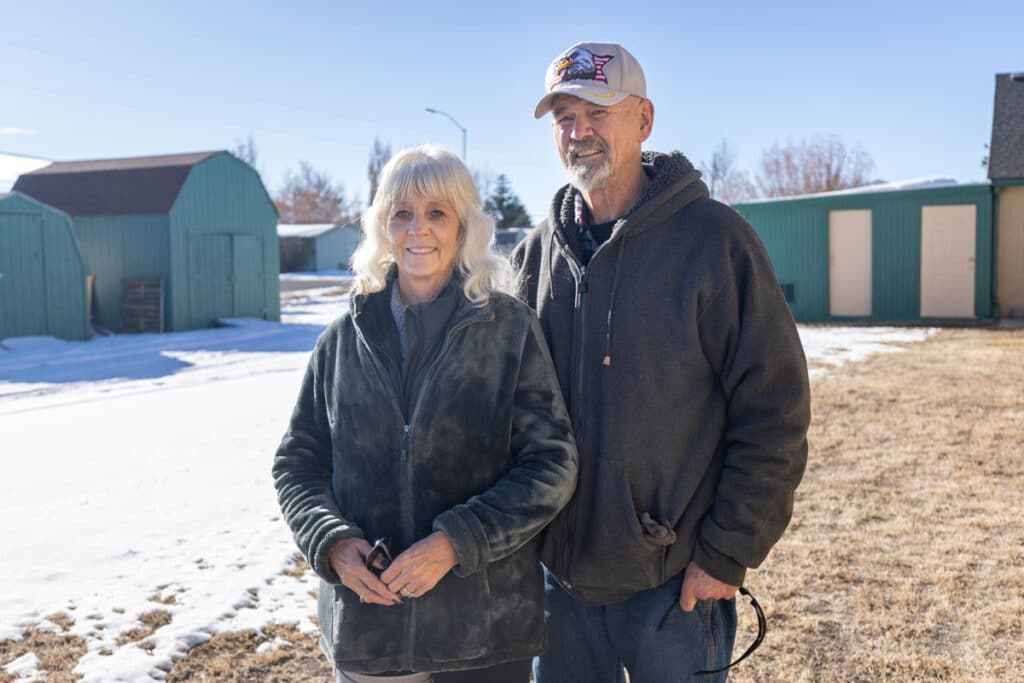 Gaye and Kevin Kearn standing outside in front of church and nearby barn.