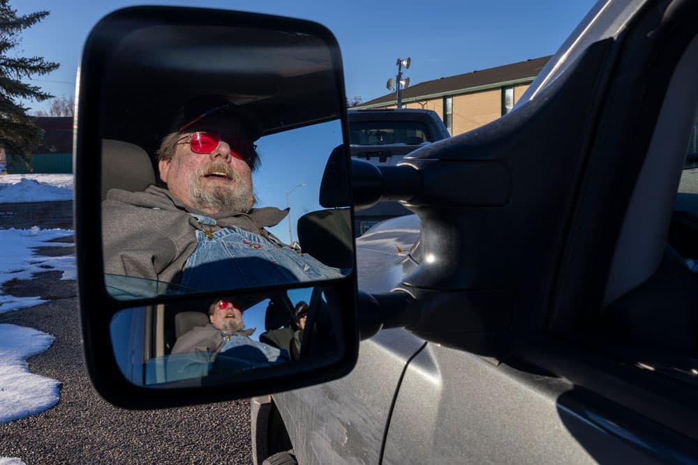 Reflection of a man in side car mirror.