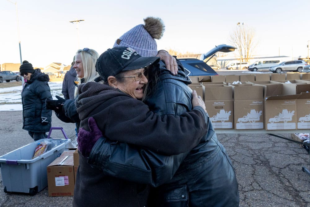 Neighbor and volunteer hugging and smiling.