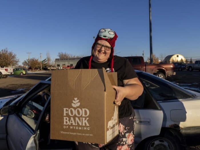 Food recipient holding a Food Bank of Wyoming box outside at a distribution.