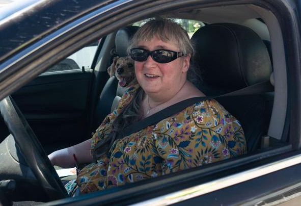 Woman sitting in driver seat of car wearing sunglasses.