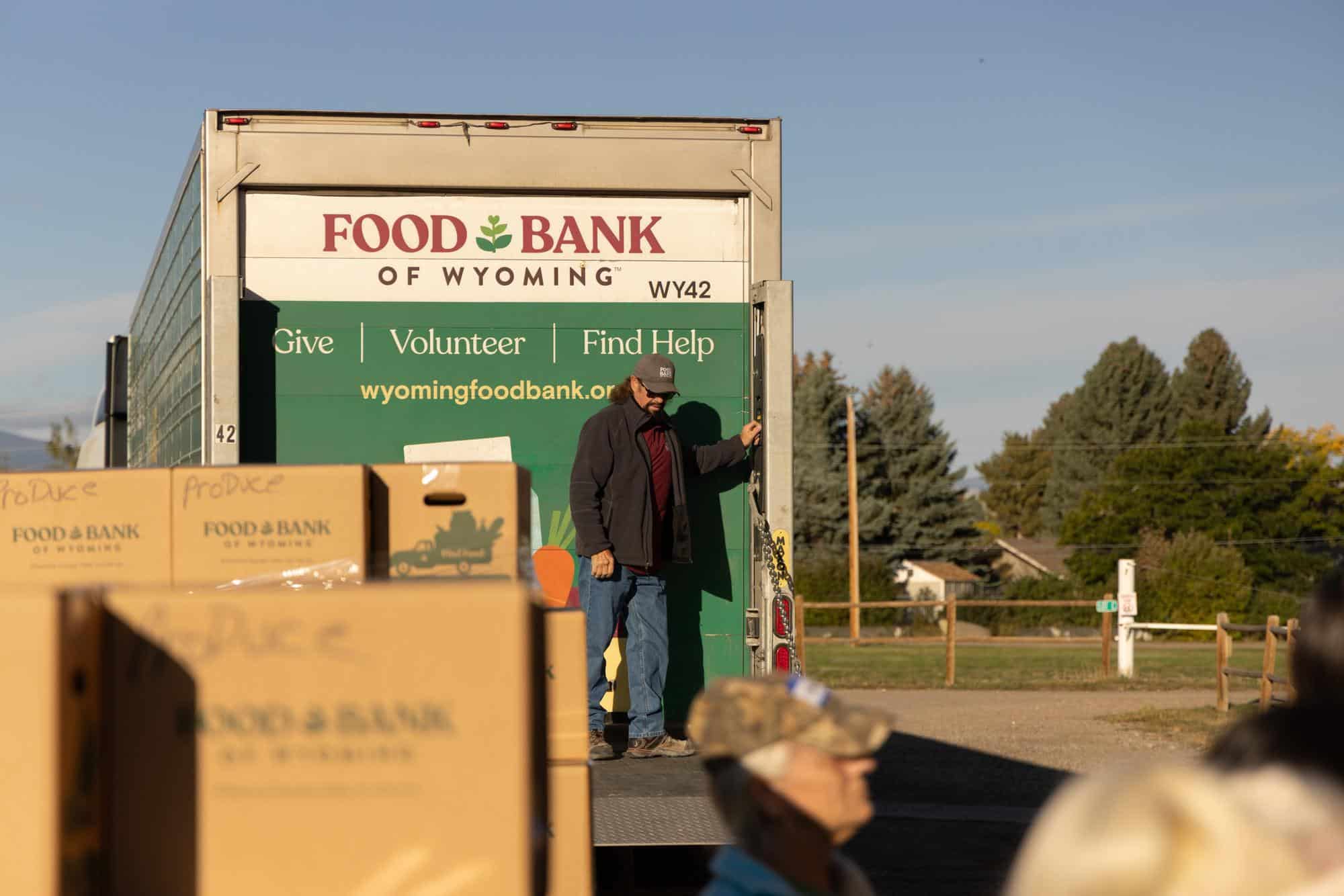 A Food Bank of Wyoming team member standing on the back of a delivery truck.