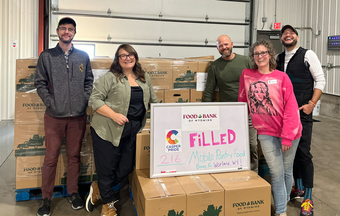Volunteers standing around and leaning on food boxes they just packed, with a sign that says "Filled."