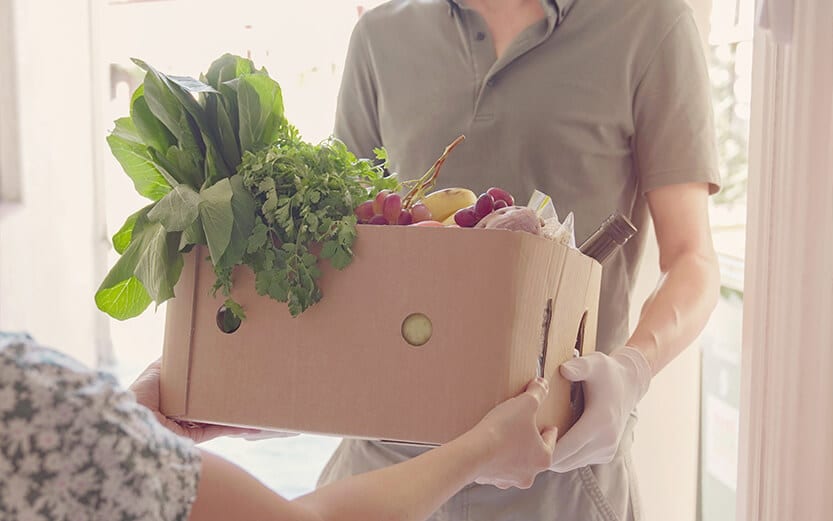 Woman's arms holding a box filled with fresh produce
