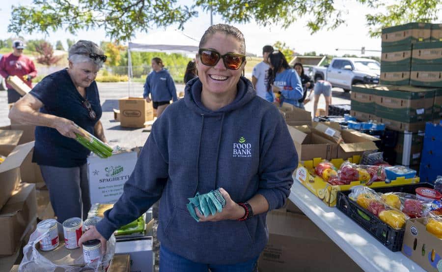 Executive Director Danica Sveda at a mobile pantry distribution holding food and smiling.