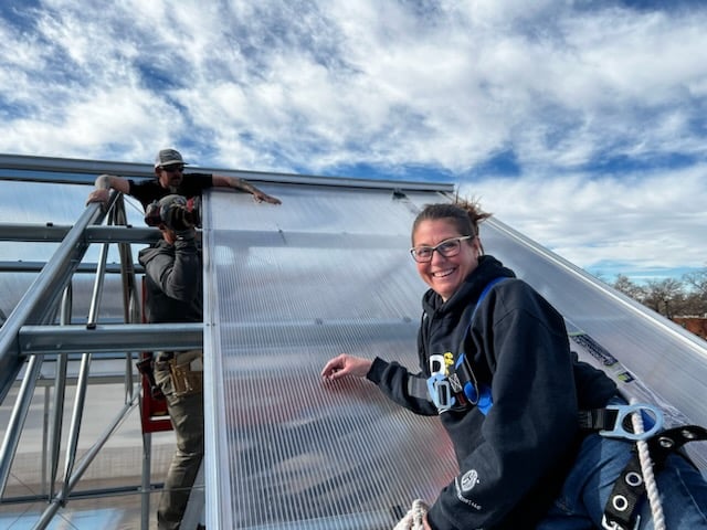 Danica Sveda helping to put a roof on a greenhouse