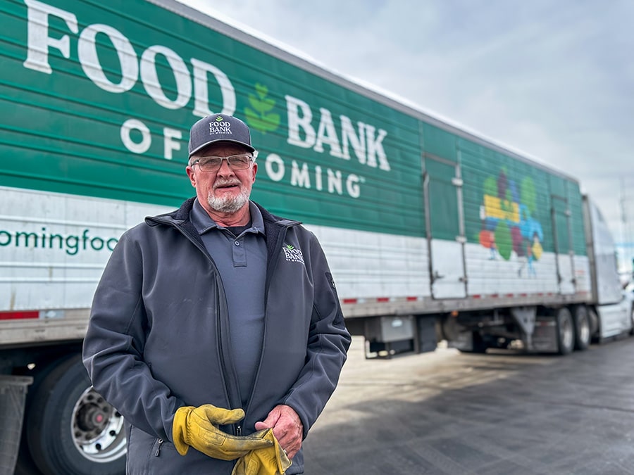 Truck driver standing in front of Food Bank of Wyoming truck.