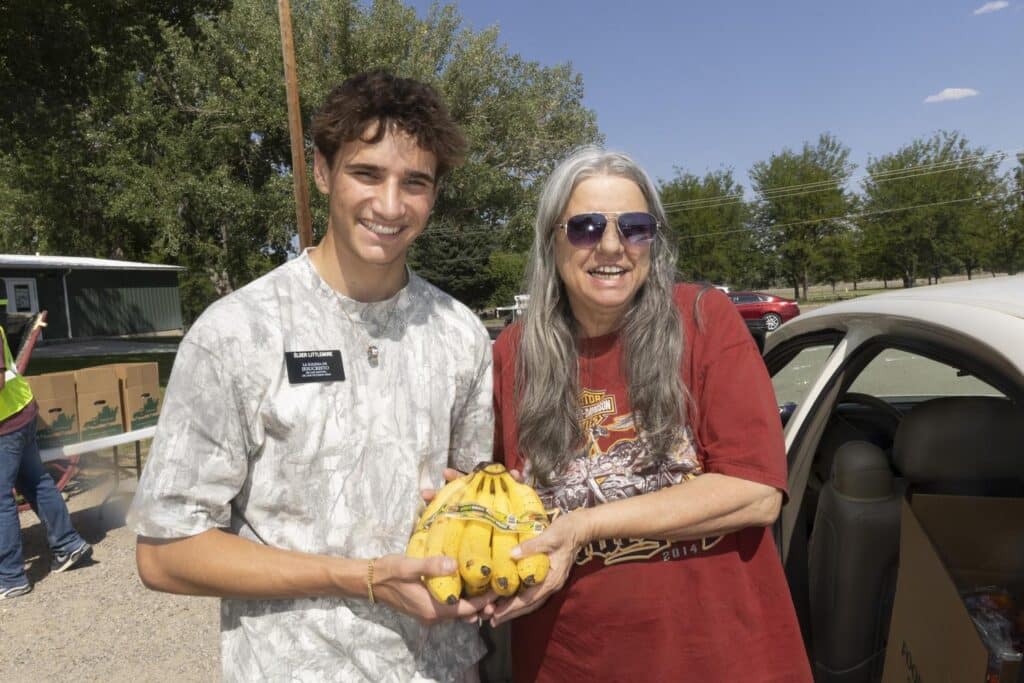 Volunteer with neighbor holding bananas.