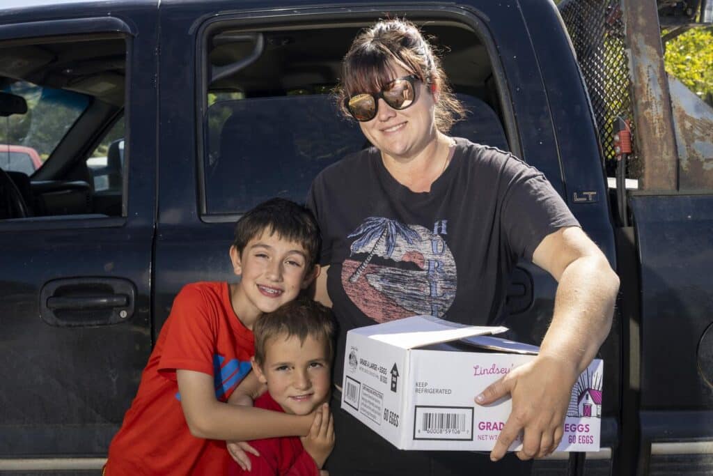 Woman with two sons holding a box of eggs.