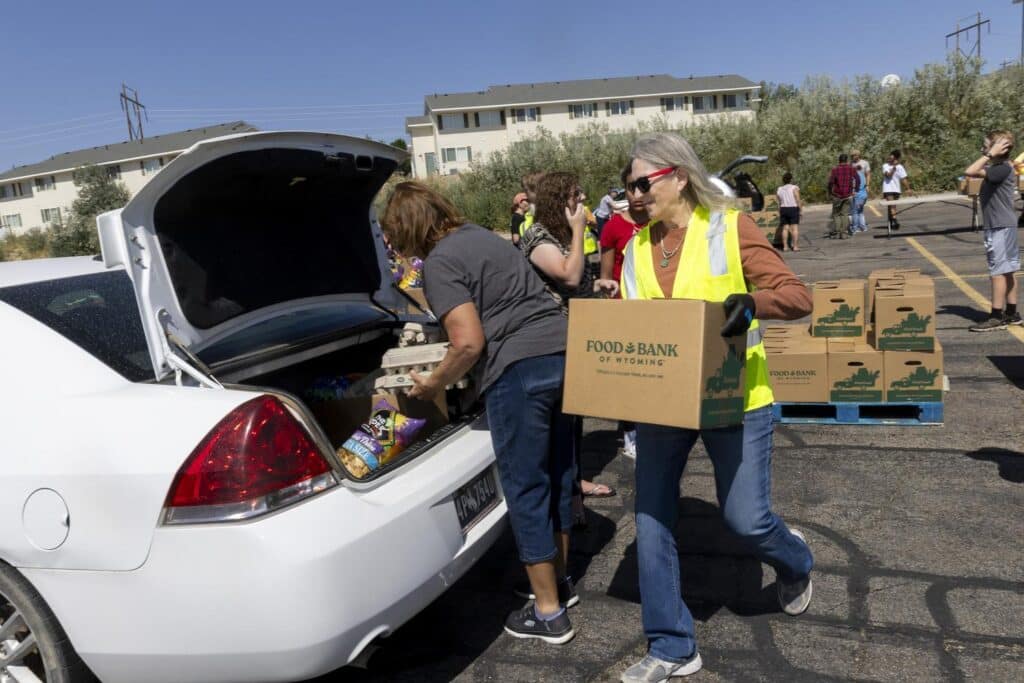 Woman carrying box to trunk of car.