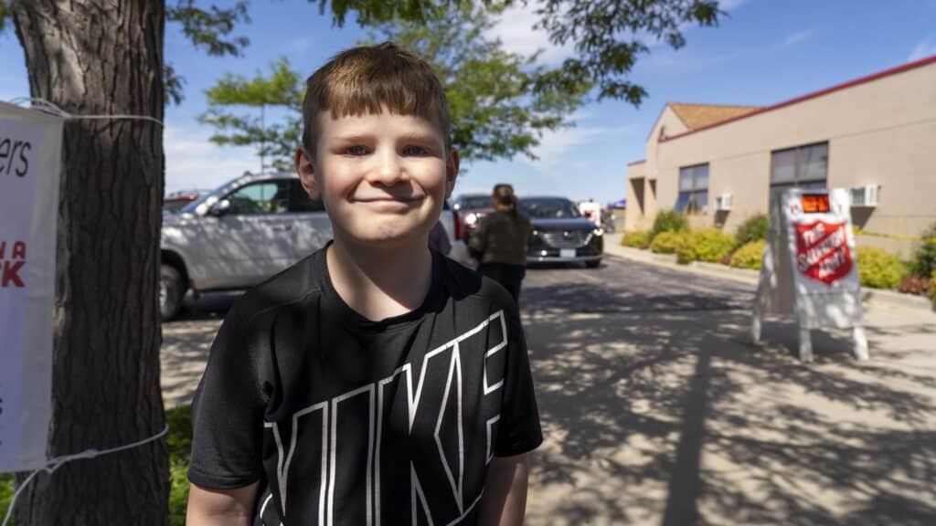 a child smiling, standing outside