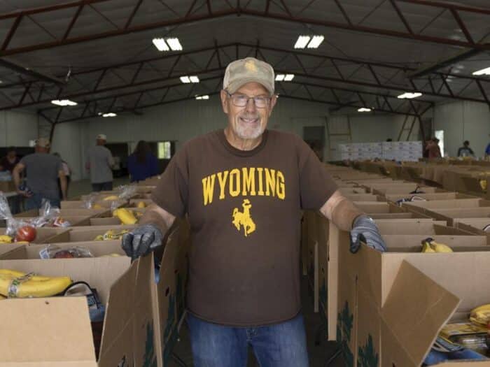 Man standing between rows of open boxes.