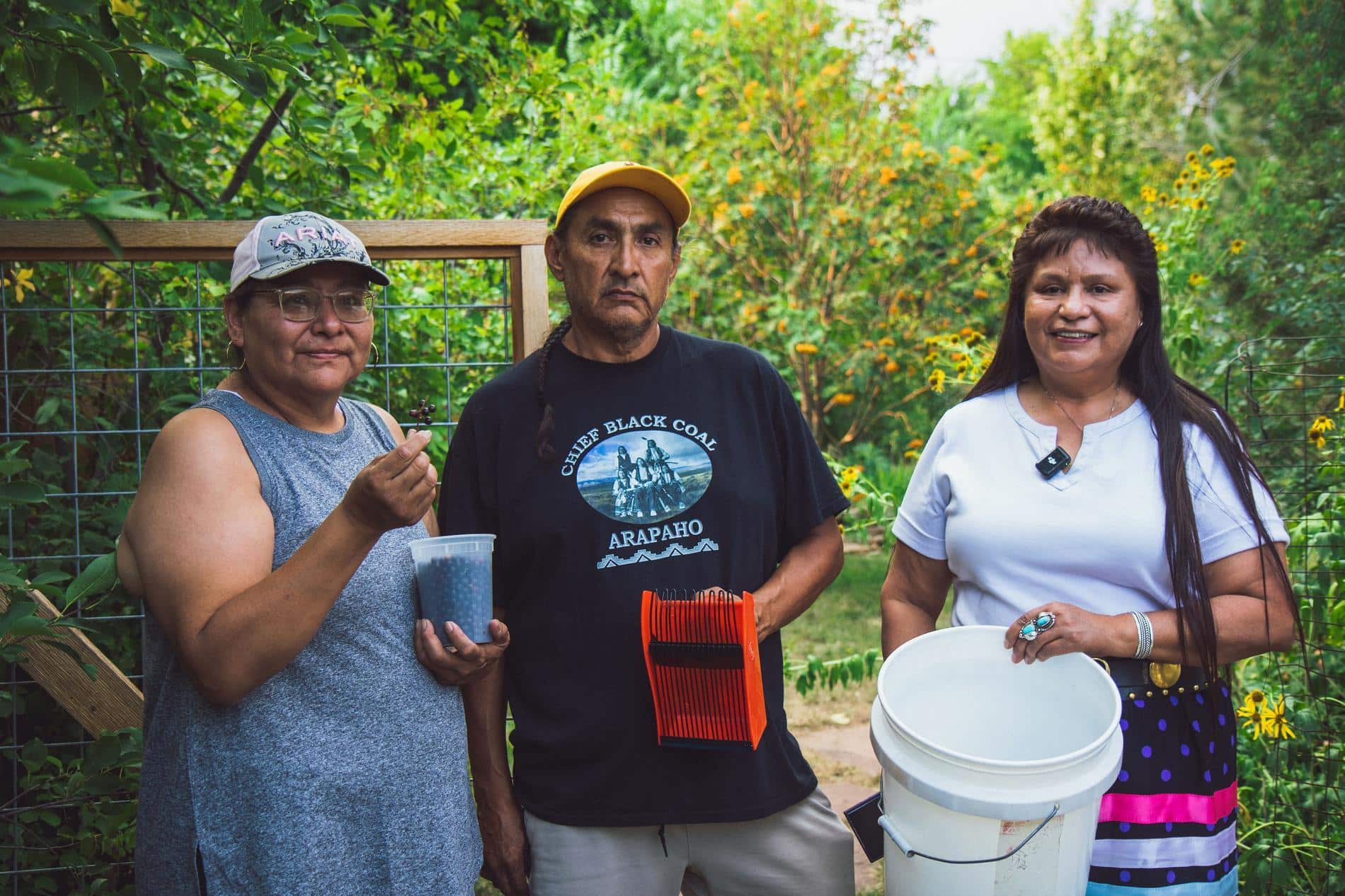 Workers pose for camera showing the chokecherries they picked.