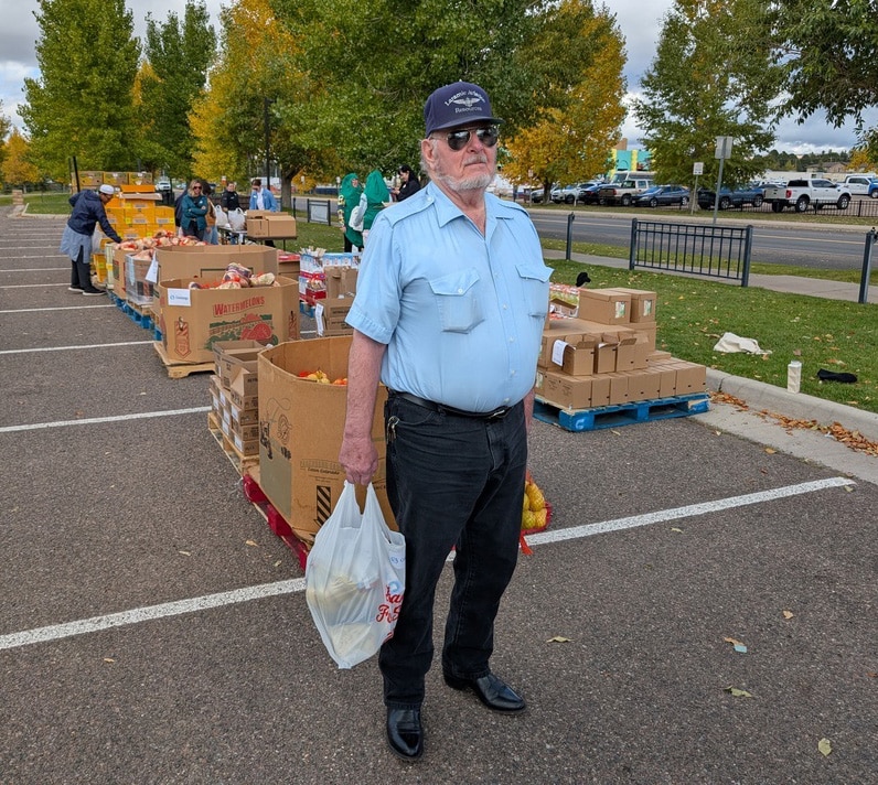 a man standing in the parking lot of a mobile food pantry in Wyoming.