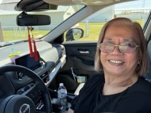 Woman sitting in her car smiling.