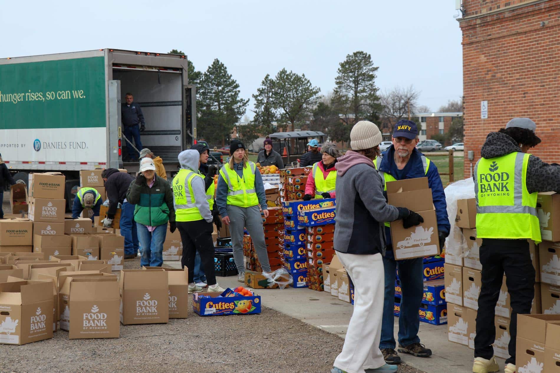 Large group of volunteers outside at a mobile pantry food distribution, sorting and packing boxes. Truck in the background.