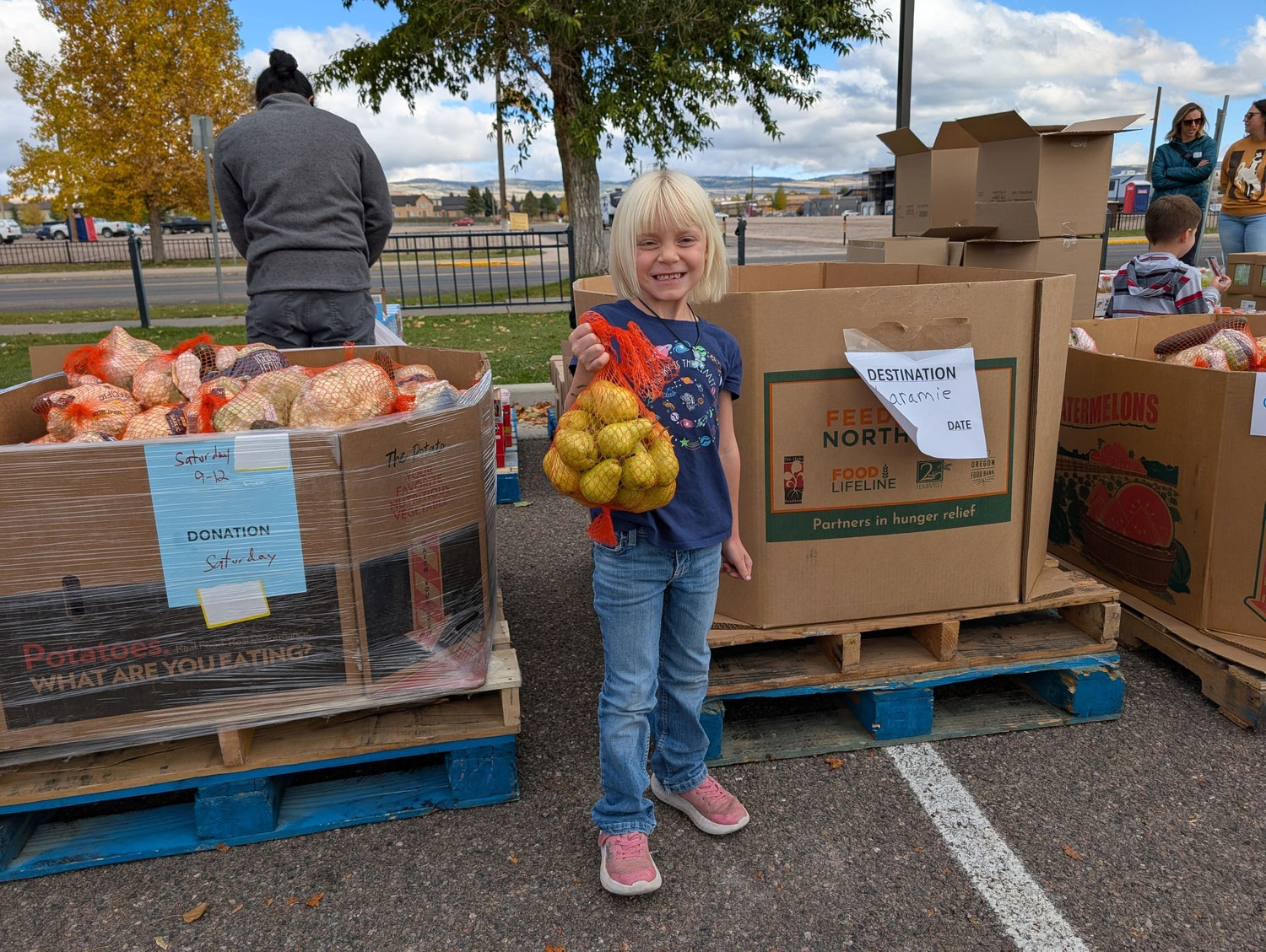 Smiling girl holds a bag of pears at a Food Bank of Wyoming volunteer site